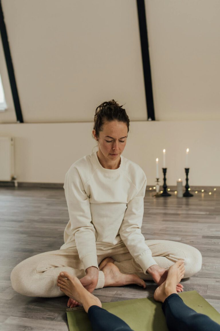 A serene indoor meditation therapy session with a woman in comfortable attire facilitating a calming environment.
