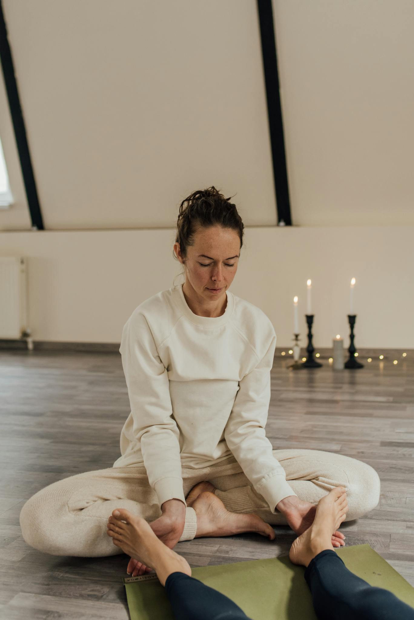 A serene indoor meditation therapy session with a woman in comfortable attire facilitating a calming environment.